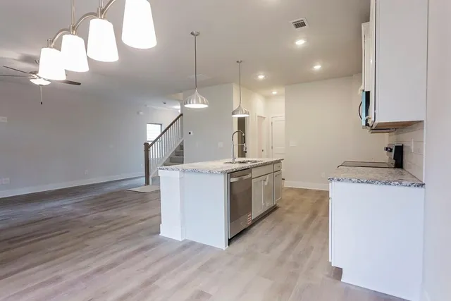 a kitchen with kitchen island a stove a wooden floor and a sink