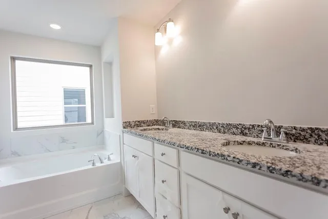 a bathroom with a granite countertop sink and a bathtub