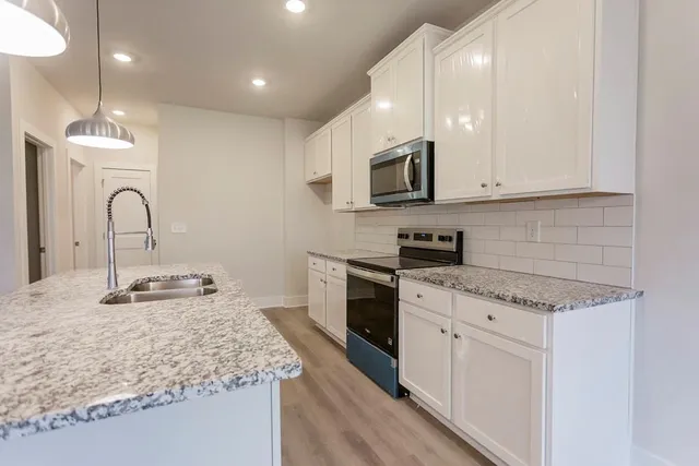 a kitchen with stainless steel appliances granite countertop a sink stove and cabinets