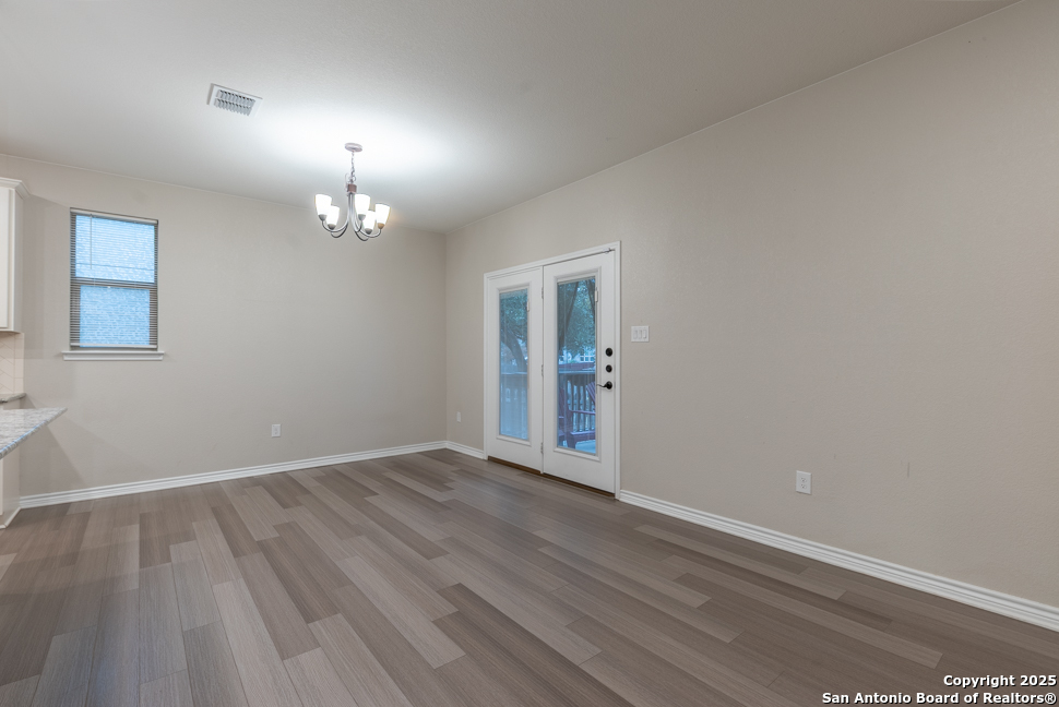 8026 San Mirienda Boerne, TX 78015 - Photo 11 of 29 an empty room with wooden floor chandelier and windows