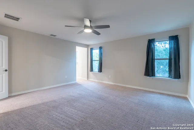 a view of an empty room with window and chandelier fan