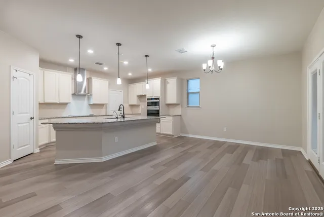 a large kitchen with granite countertop a large counter top a sink stainless steel appliances and cabinets