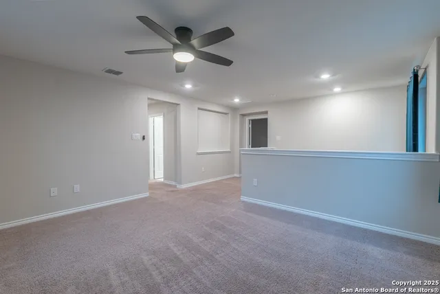 an empty room with ceiling fan and windows