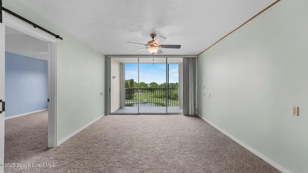 a view of a room with a ceiling fan and window