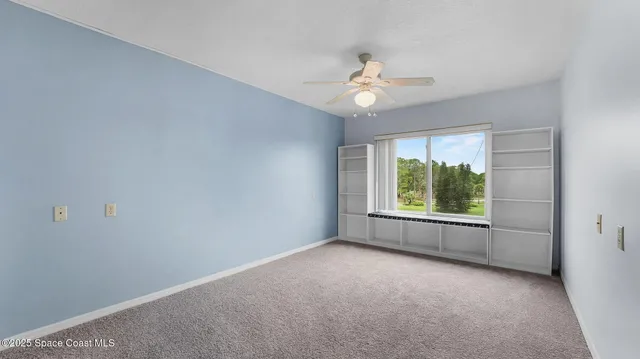 an empty room with windows and chandelier fan