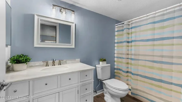 a bathroom with a sink a mirror a toilet and shower curtain