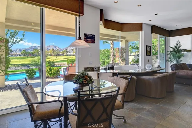 a dining room with furniture large windows and wooden floor