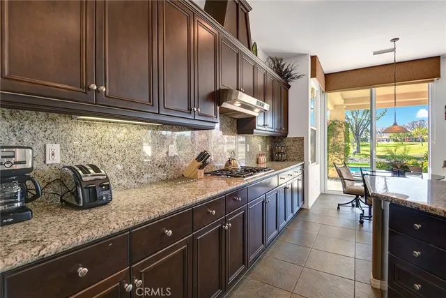 a kitchen with granite countertop a sink a stove and wooden cabinets