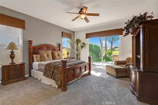 a spacious bedroom with a bed a chandelier and a flat tv screen