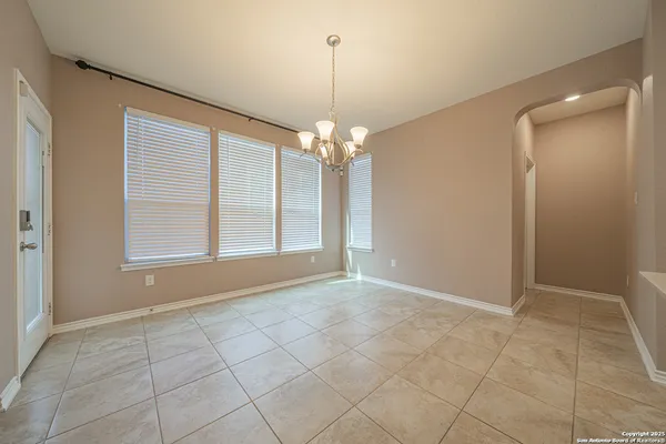 a view of an empty room with window and chandelier fan