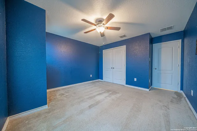 an empty room with windows and fan