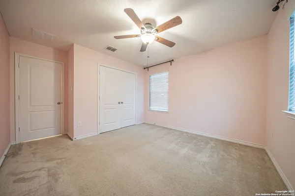 an empty room with windows and fan