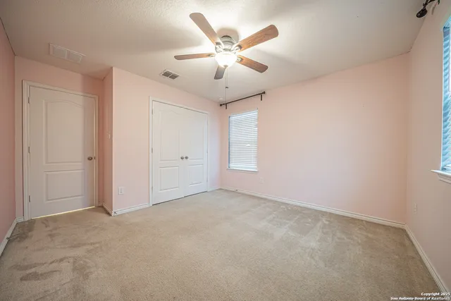 an empty room with windows and fan