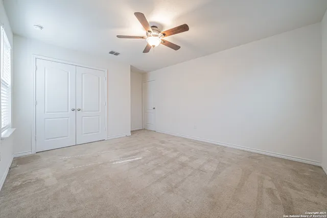 a view of an empty room with chandelier fan and fire place