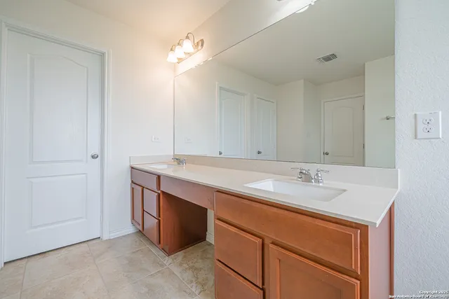 a large bathroom with a granite countertop double vanity sink a mirror and a bathtub