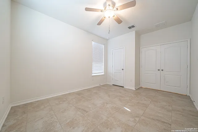 an empty room with windows and fan