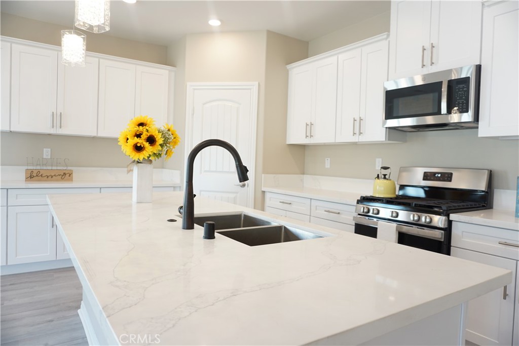 128 Chumash Perris, CA 92570 - Photo 5 of 22 a kitchen with stainless steel appliances granite countertop a sink a stove top oven a chimney and a center island