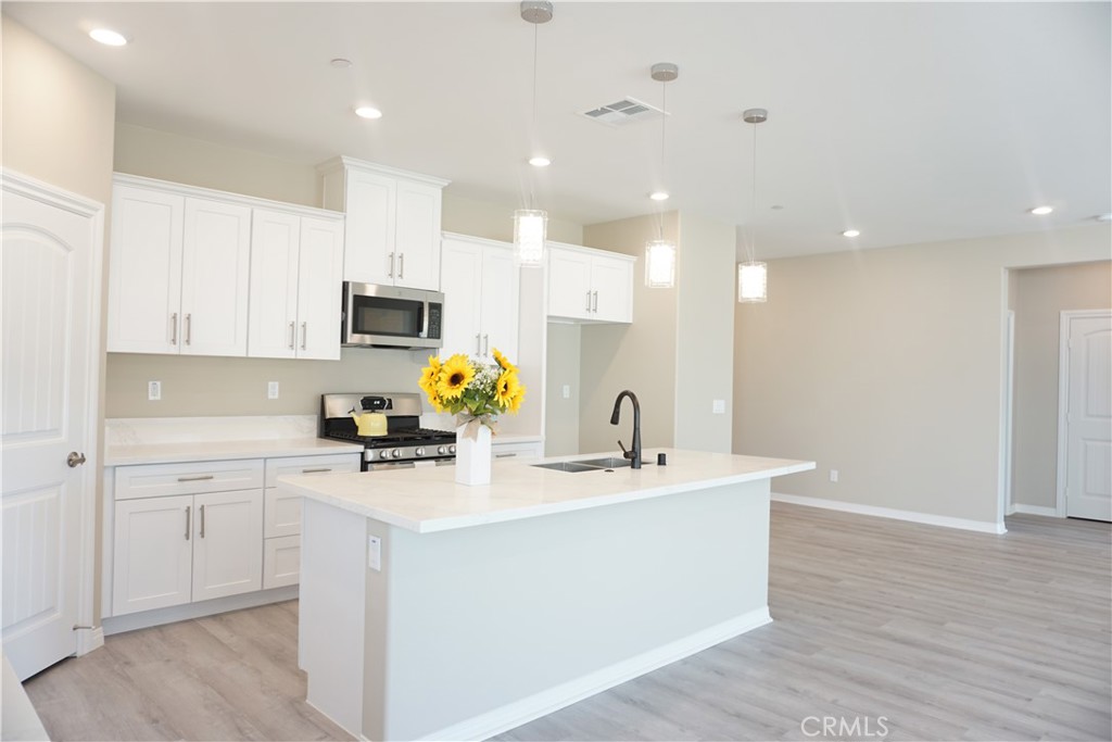 128 Chumash Perris, CA 92570 - Photo 7 of 22 a kitchen with a sink a stove a microwave and cabinets