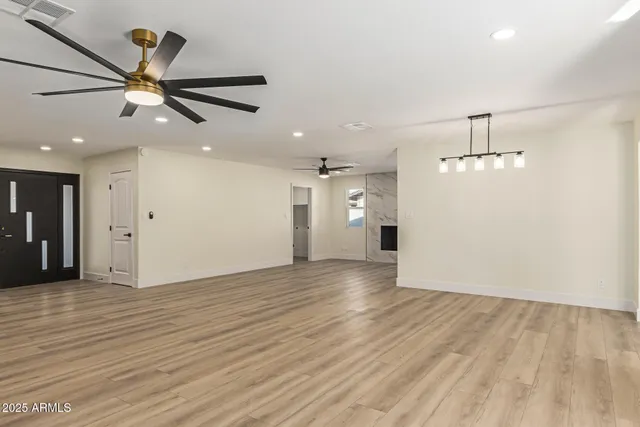 an empty room with wooden floor fan and windows
