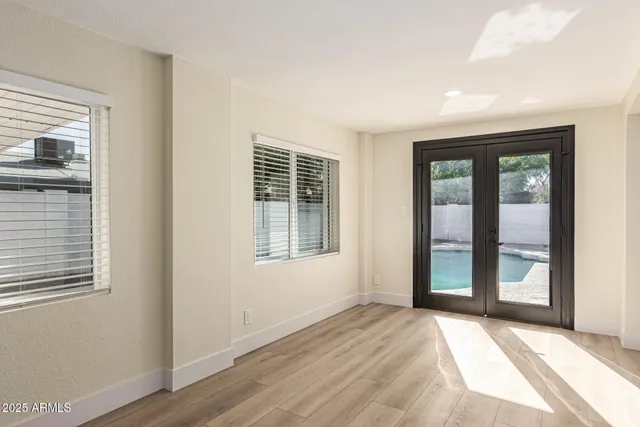 a view of an empty room with wooden floor and a window