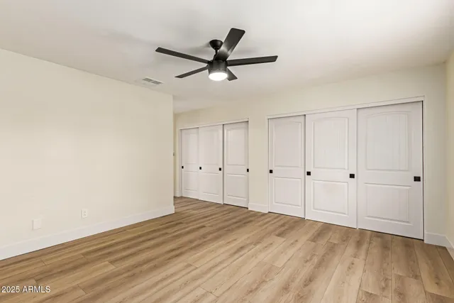 a view of empty room with wooden floor and ceiling fan