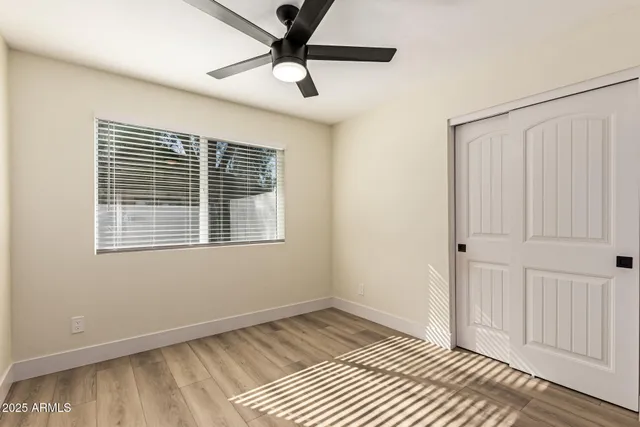 a view of an empty room with a window and wooden floor