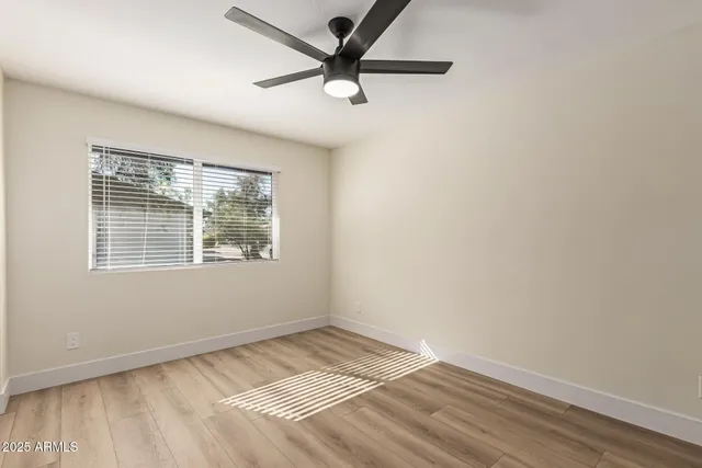 an empty room with a window and a ceiling fan