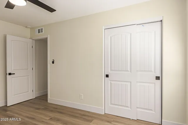 an empty room with wooden floor closet and windows