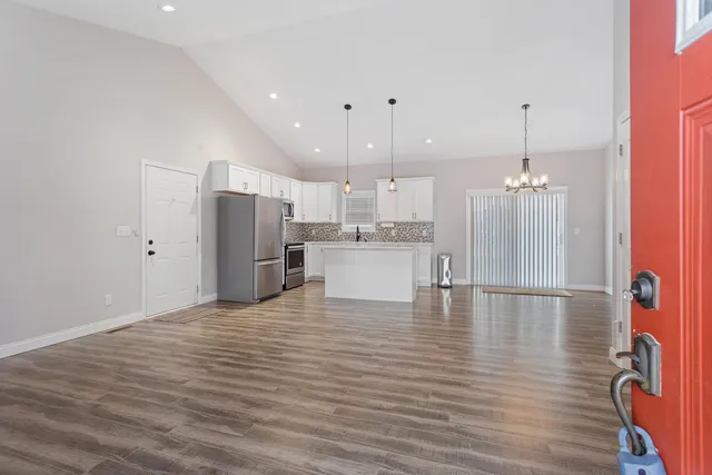 a kitchen with stainless steel appliances granite countertop a refrigerator oven a sink dishwasher and white cabinets with wooden floor