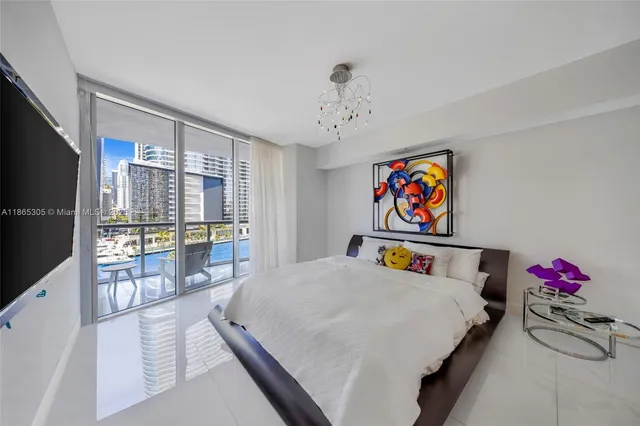 a bedroom with a bed a flat screen tv and a chandelier