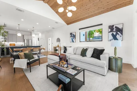 a living room with furniture kitchen view and a chandelier