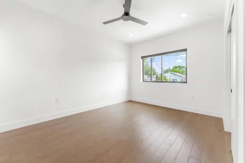 an empty room with wooden floor ceiling fan and windows