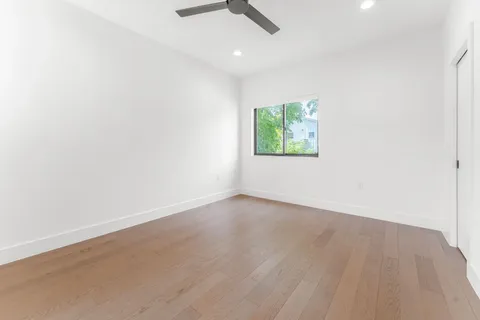 an empty room with wooden floor chandelier fan and windows