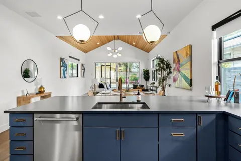 a kitchen with kitchen island granite countertop a sink cabinets and stainless steel appliances