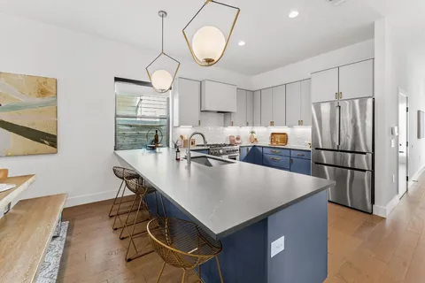 a kitchen with stainless steel appliances granite countertop a table chairs a refrigerator and a sink
