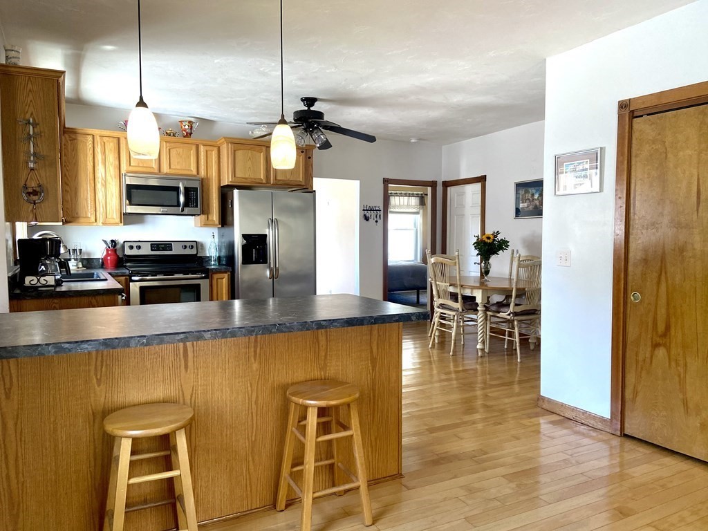 48 Pine Street Rochester, MA 02770 - Photo 20 of 39 a kitchen with stainless steel appliances granite countertop a refrigerator a stove a dining table and chairs with wooden floor