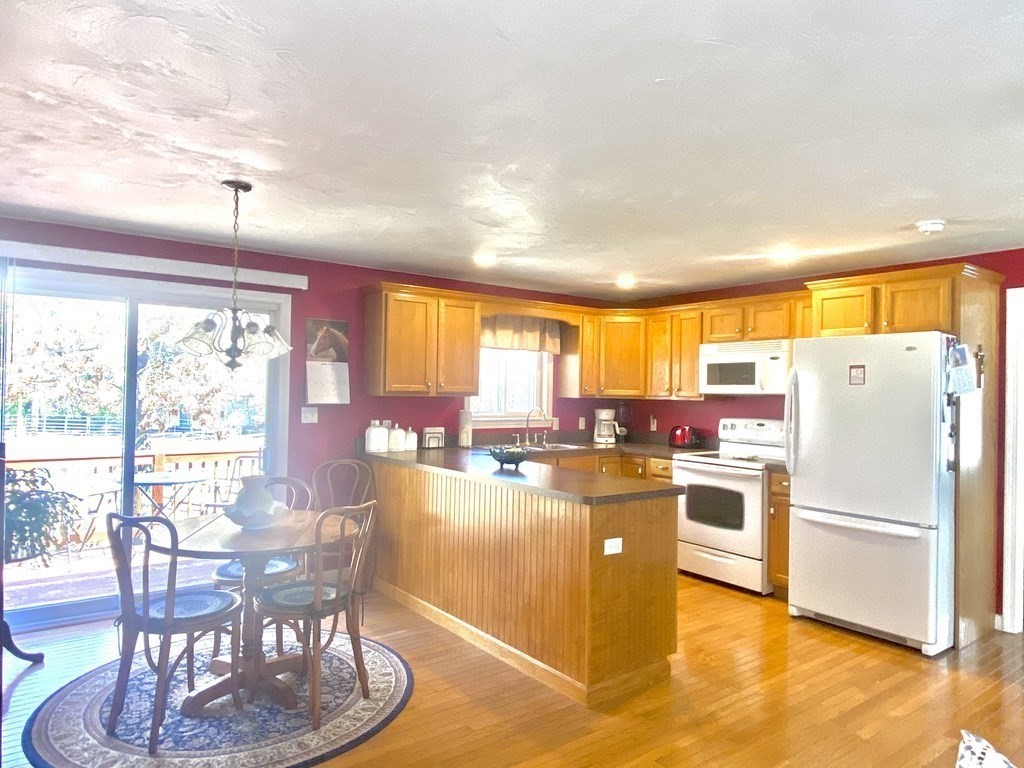 48 Pine Street Rochester, MA 02770 - Photo 34 of 39 a kitchen with a table chairs refrigerator and cabinets