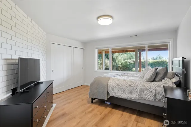 a bedroom with a bed and a flat tv screen next to a window