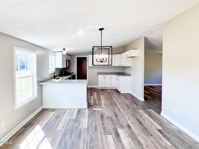 a kitchen with granite countertop a stove top oven a sink dishwasher and a refrigerator with wooden floor