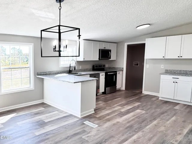 a kitchen with granite countertop a sink cabinets stainless steel appliances and a window