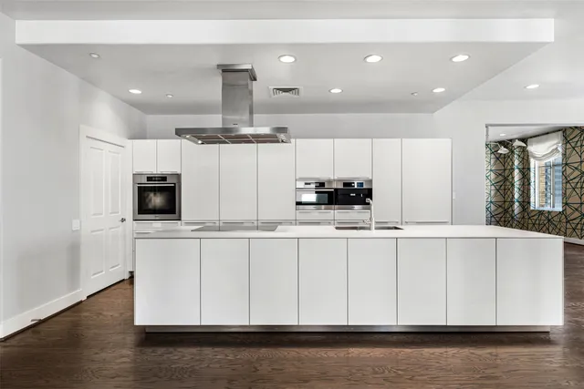 a large white kitchen with lots of counter space and wooden floor
