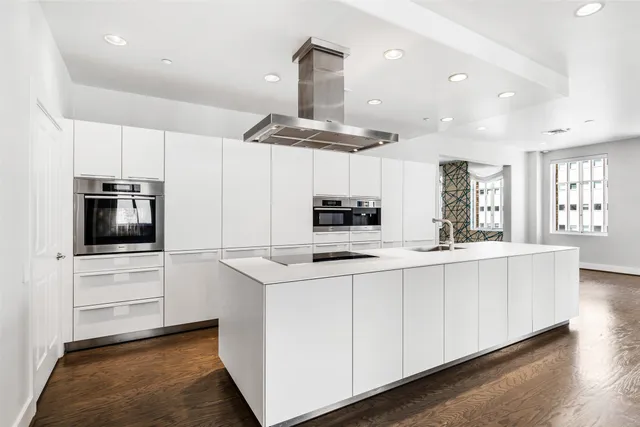 a kitchen with stainless steel appliances a sink a stove a microwave a center island and cabinets