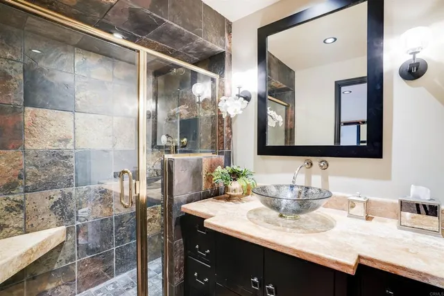 a bathroom with a granite countertop sink a mirror and shower