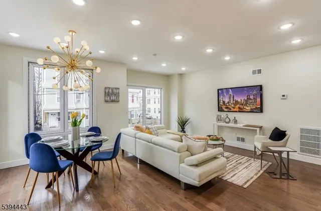 a living room with furniture a chandelier and a flat screen tv