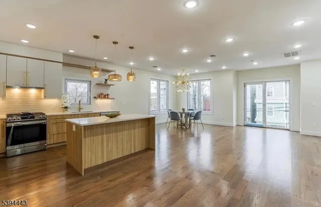 a large kitchen with stainless steel appliances granite countertop a large counter top a stove a chimney a sink and a refrigerator