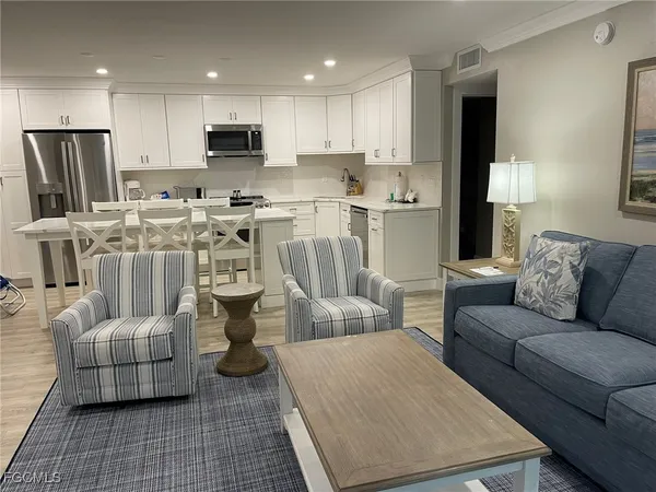 a kitchen with stainless steel appliances granite countertop a stove a sink a microwave a refrigerator and white cabinets