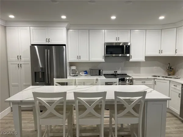 a kitchen with stainless steel appliances kitchen island a sink a stove a microwave and cabinets