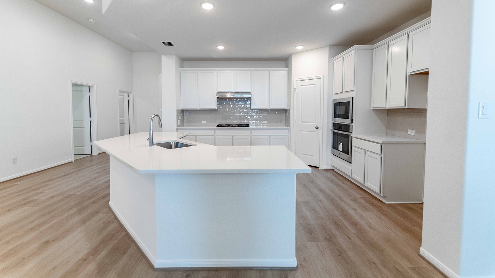 251 Grey Leaf Road Buda, TX 78610 - Photo 6 of 17 Kitchen featuring backsplash, an island with sink, white cabinetry, light wood-style floors, and recessed lighting