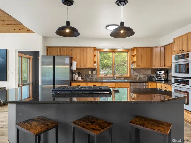 a kitchen with stainless steel appliances granite countertop a stove a sink and a refrigerator with wooden floor