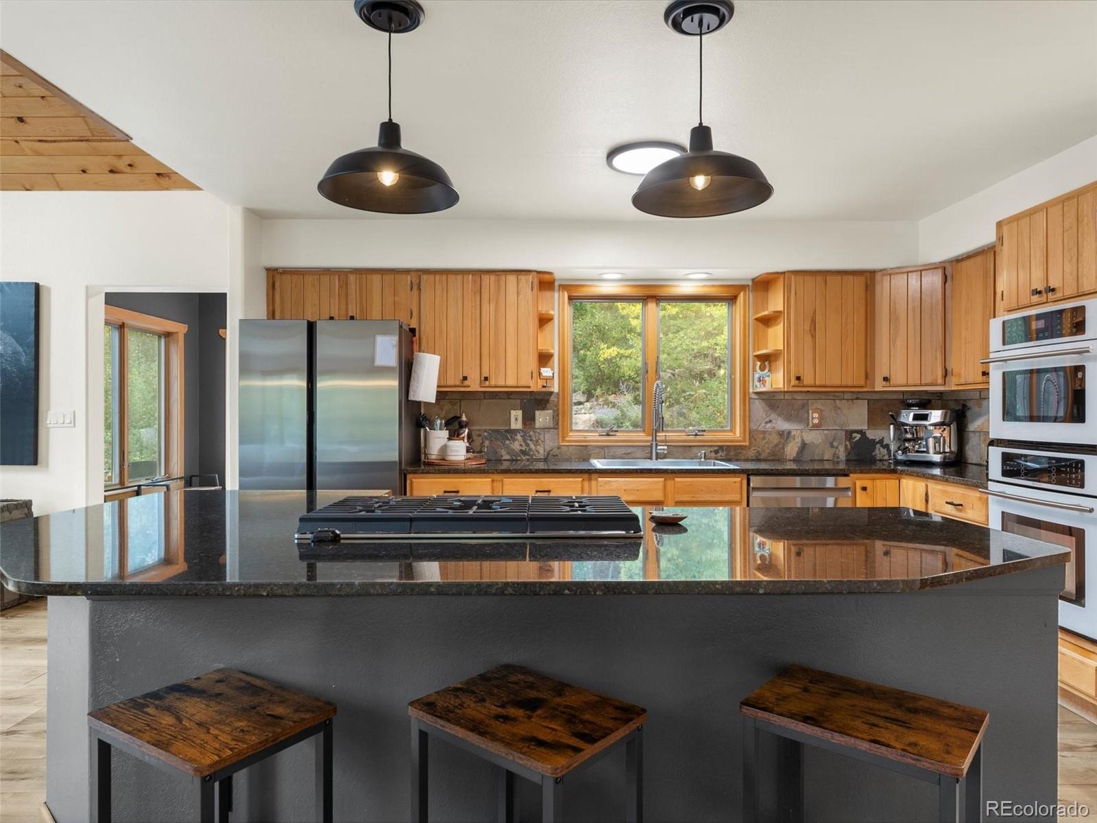 9459 South Turkey Creek Road Morrison, CO 80465 - Photo 5 of 25 a kitchen with stainless steel appliances granite countertop a stove a sink and a refrigerator with wooden floor